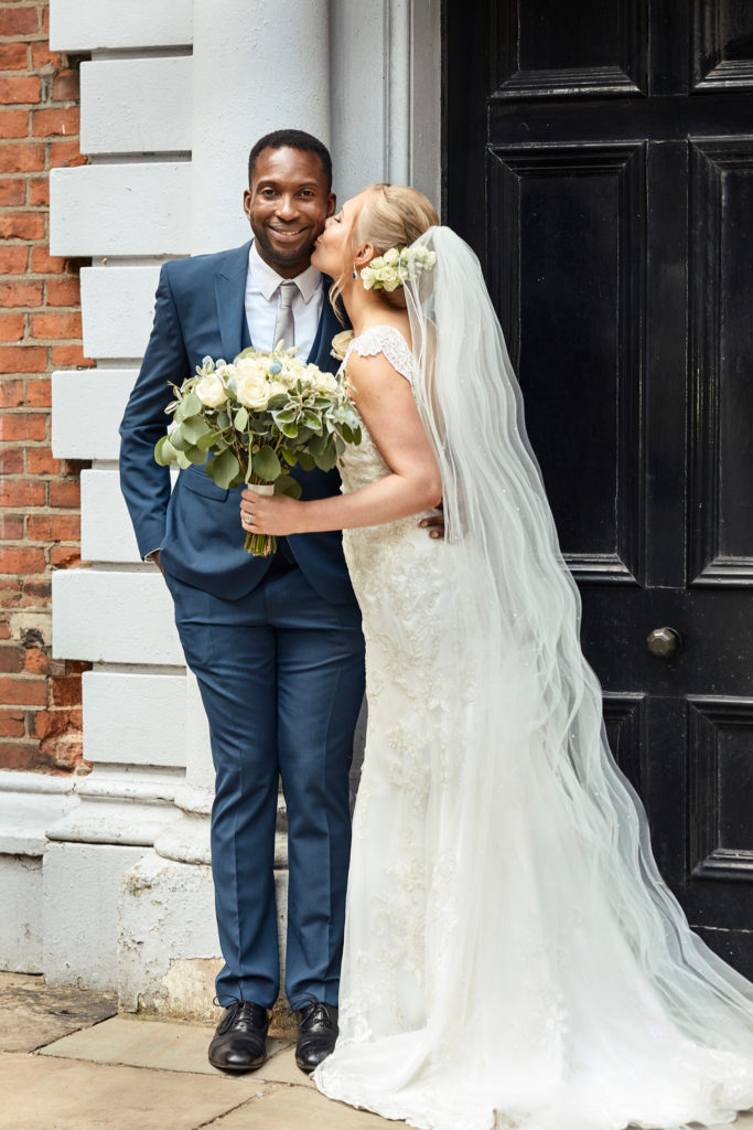 Bride and groom smiling together in front of a black panelled door in central London